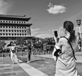 <br>          　　　　蓝天白云下的北京，景色宜人，游客在前门步行街拍照留念。<br><br>        